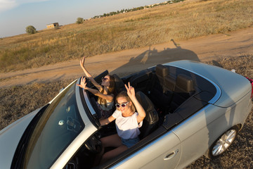 Two attractive young women in a cabriolet car