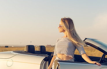  attractive young woman near a convertible car