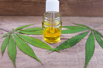 Green leaves of medicinal cannabis with extract oil on a wooden table