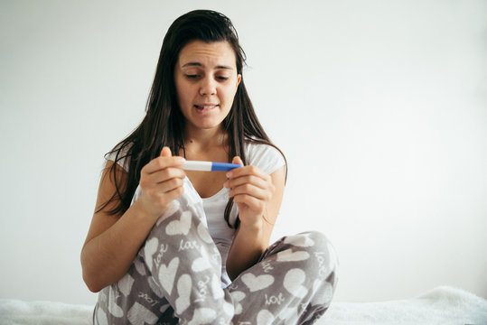 woman in bed surprised by pregnancy test