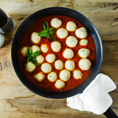 meatballs from ricotta cheese in pan with tomato sauce on wooden table