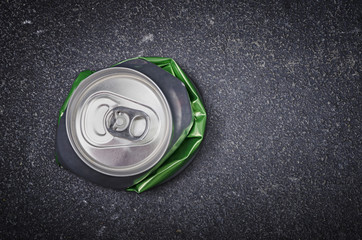 Crushed aluminium beer can on asphalt street background
