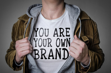 Man showing You Are Your Own Brand tittle on t-shirt. Personal branding concept. - obrazy, fototapety, plakaty