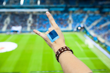 Fans arm with sticker gestures during cheering on football game on green grass background