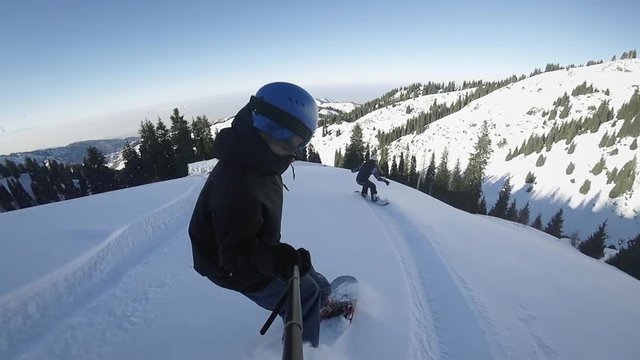 Close up of extreme snowboarders riding by powder by GoPro