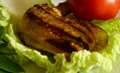 Grilled chicken leg with salad and tomatoe on a white plate