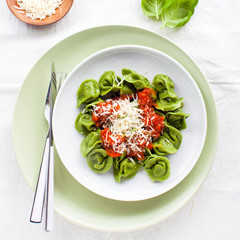 classic homemade Italian tortellini with spinach and ricotta, spring style and red wine in wineglass
