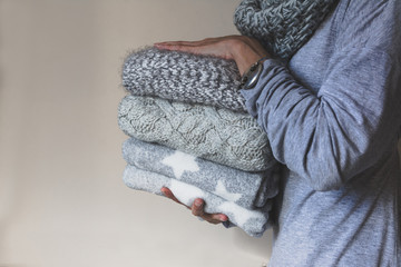 Woman holding a pile of winter wool clothes