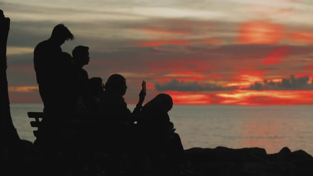 Sunset by the ocean. Calm water.People admire the sunset and take pictures of it. Silhouette