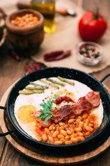 english breakfast with eggs, tomatoes, mushrooms, bacon, beans, and sausage