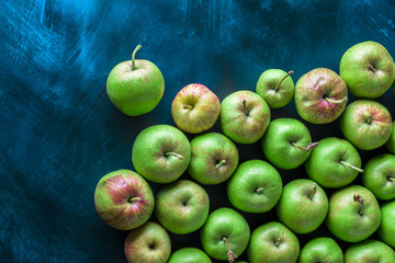 Green and red large overhead colorful group of organic apples on rustic blue table in studio