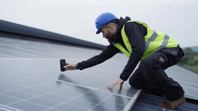 Technician with computer checking panels at solar energy installation
