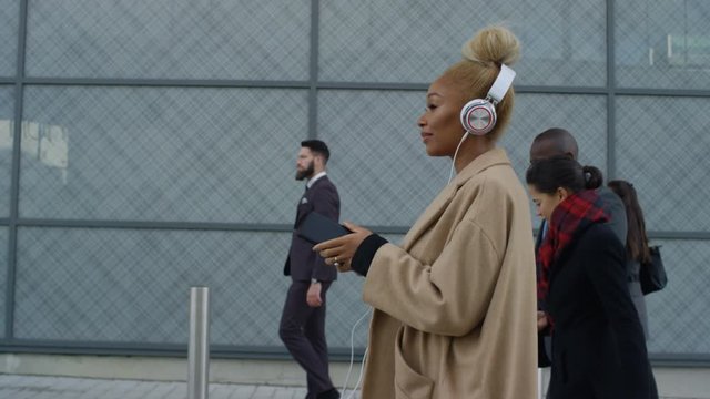  Relaxed businesswoman wearing headphones as she walks to work