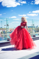  beautiful young girl on the roof of a building in a red lush dress