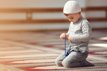 The Muslim child prays in the mosque, the little boy prays to God, Peace and love in the holy month...