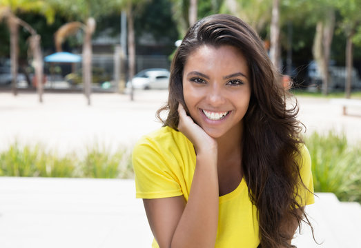 Flirting latin woman in yellow shirt looking at camera