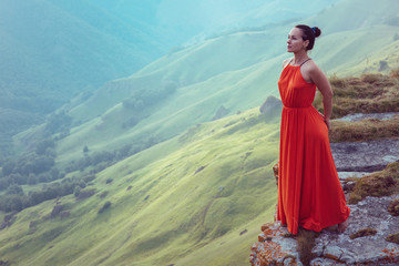 Girl in red dress on the edge of a cliff