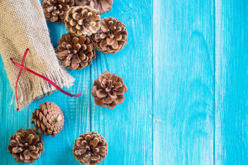 Christmas background. Fir cones and gift bag on blue wooden background with copy space. Christmas or New Year card template.