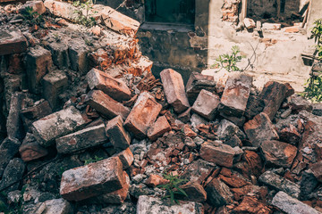 Red bricks of destroyed house by war, hurricane or other natural catastrophe or disaster, ruins of...