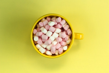 top view yellow cup with marshmallows on bright background