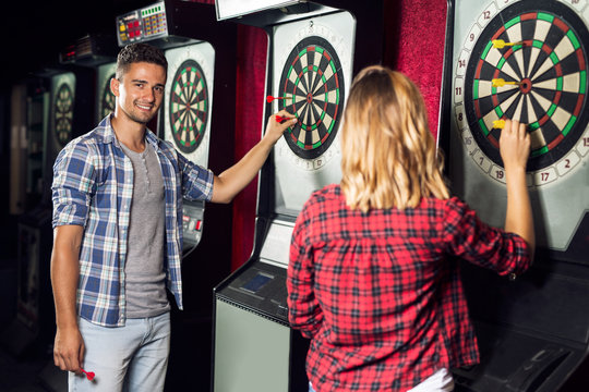 Young couple flirting and playing darts