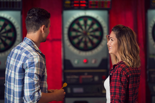 Young couple flirting and playing darts