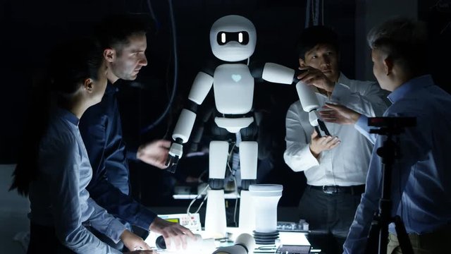  Electronics engineers collaborating on design of robot in dark lab