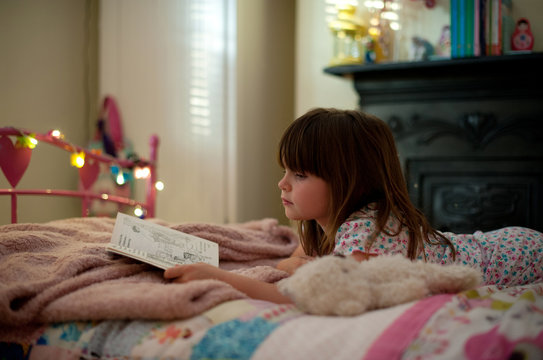 Girl laying on her bed reading