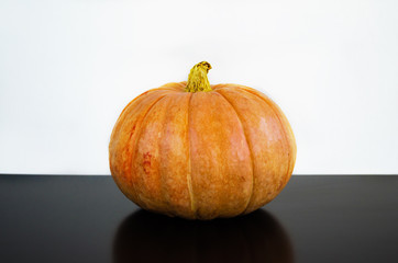 Yellow ripe pumpkin of perfect shape on a black table on a white background