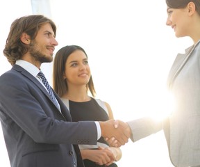 Businesspeople  shaking hands against room with large window loo