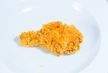 close up on crispy chicken leg fried on white plate. junk food
