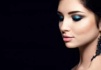 Beautiful woman portrait isolated on black background. Young lady posing with blue eye shadows and...