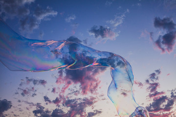 Large bubble floating along the beach at sunset.