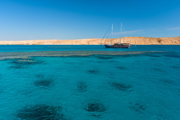 Sail boat in the coral sea near island. Summer vacation in an exotic country.