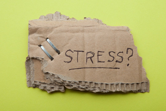 The word "stress" on an old piece of cardboard box on a bright green background.