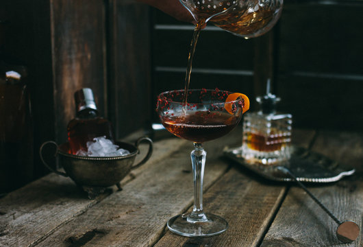 classic manhattan cocktail pouring into a champagne saucer - coupette