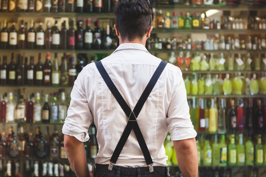 Young Man in front of a Showcase Full of Alcoholic Bottles