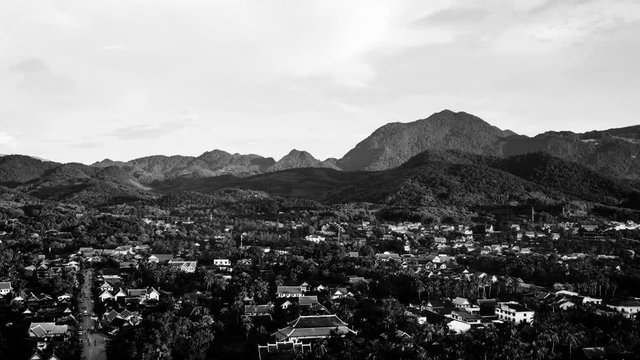 Luang Prabang, Laos. Aerial view of Luang Prabang town in Laos. Night over the small city surrounded by mountains. Colorful sunset sky. Day to night time-lapse. Black and white
