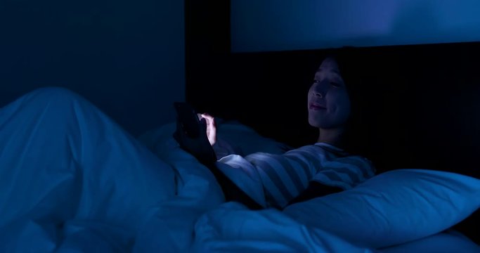 Woman using cellphone to switch off the light at home , smart home concept