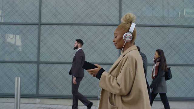 Relaxed businesswoman wearing headphones as she walks to work