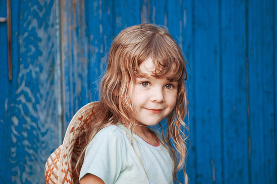 Portrait of a young girl on a blue background a wooden wall. Behind girl - Hat.