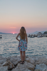 Dziewczyna nad morzem na skale patrzy na zachód słońca, morze adriatyckie, Chorwacja