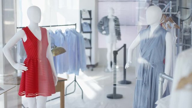Interior of women's fashion clothing store or manufacturer with clothes racks and mannequins.