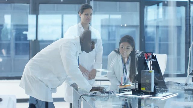  Electronics engineers working in lab, building components with 3D printer