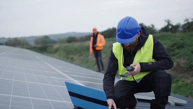  Technician with laptop checking the panels at solar energy installation