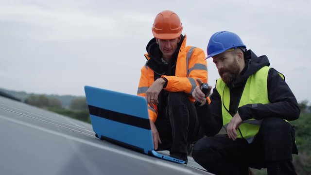 Technician with laptop checking the panels at solar energy installation