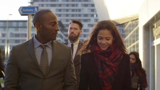  Professional group walking in the city with business man & woman chatting