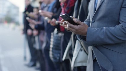 Diverse business group looking at smartphones while waiting in line - Powered by Adobe