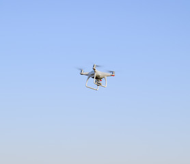 White drone against the blue evening sky. Multicopter flight.