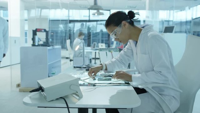  Electronics engineers working in modern lab building & testing devices